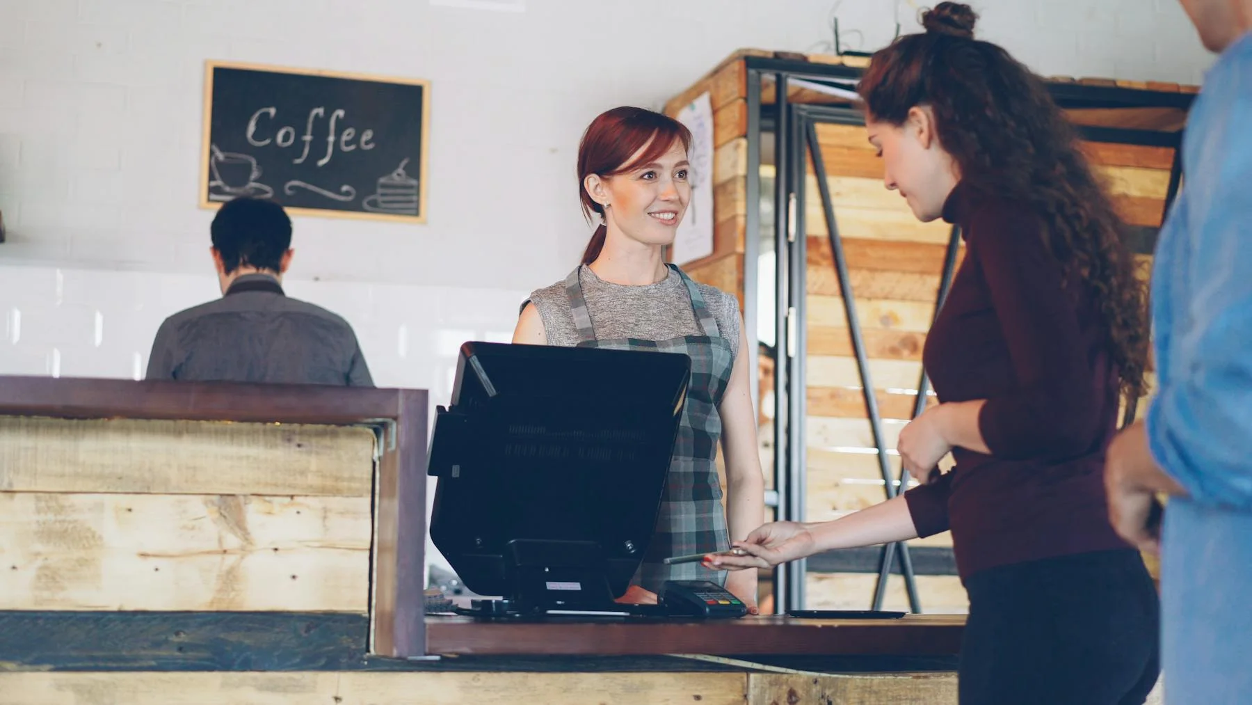 Customer and barista interacting across a warm coffee shop counter during service